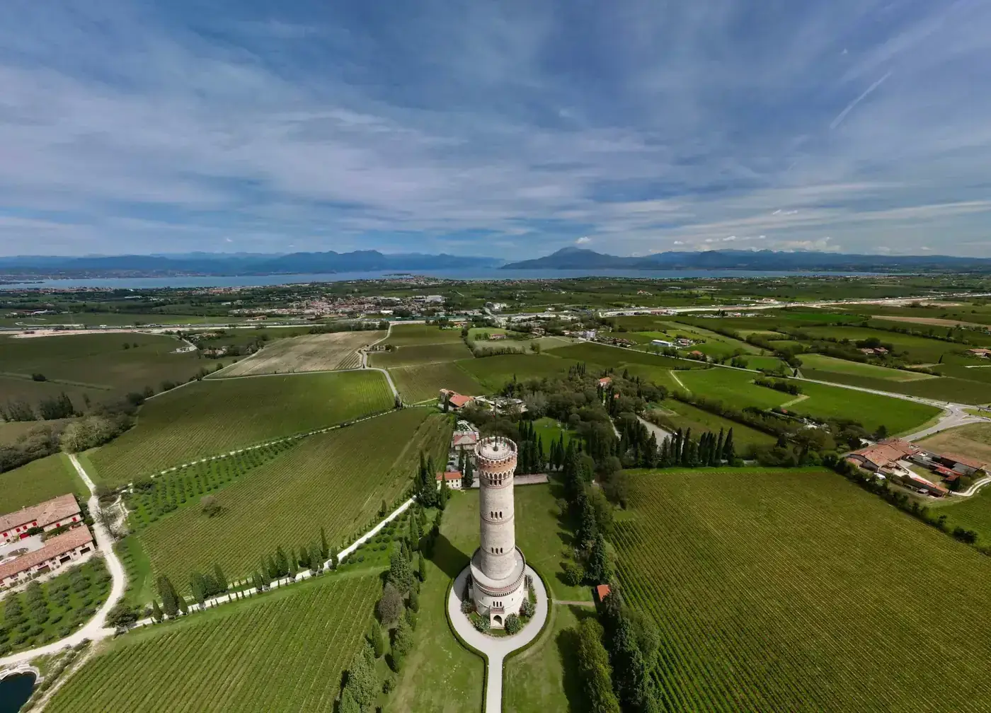 Drone shot of San Martino della Battaglia tower in Lombardy, surrounded by lush vineyards.