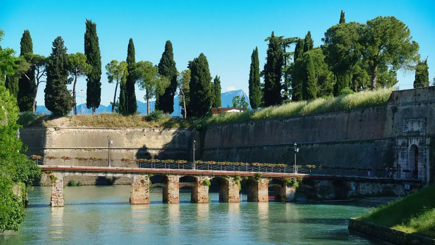 Scenic view of a historic bridge and trees in Peschiera del Garda, Italy.