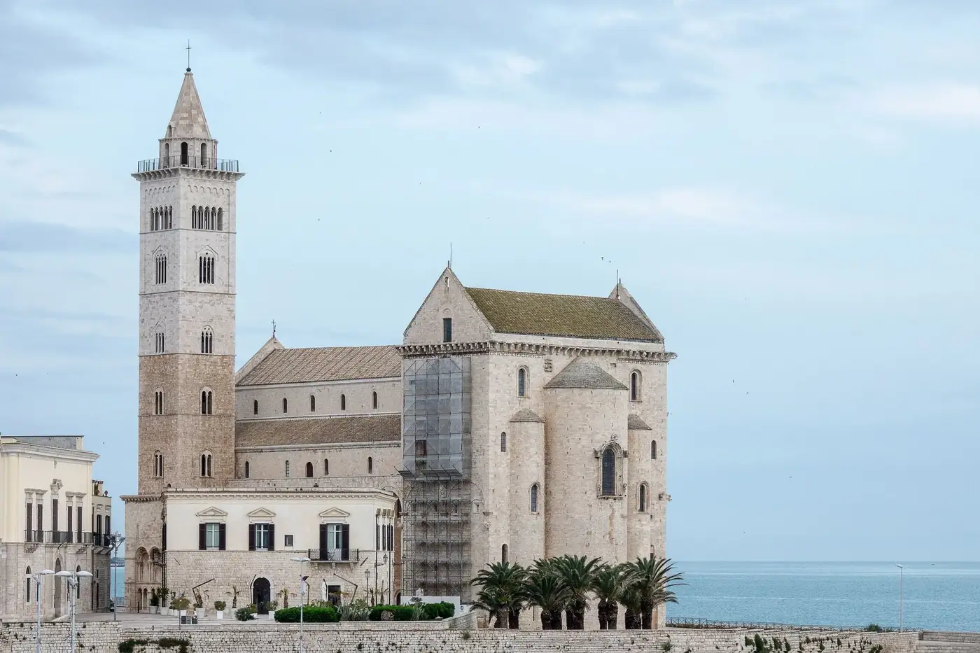 A stunning view of a historic cathedral and tower by the seaside under a blue sky.
