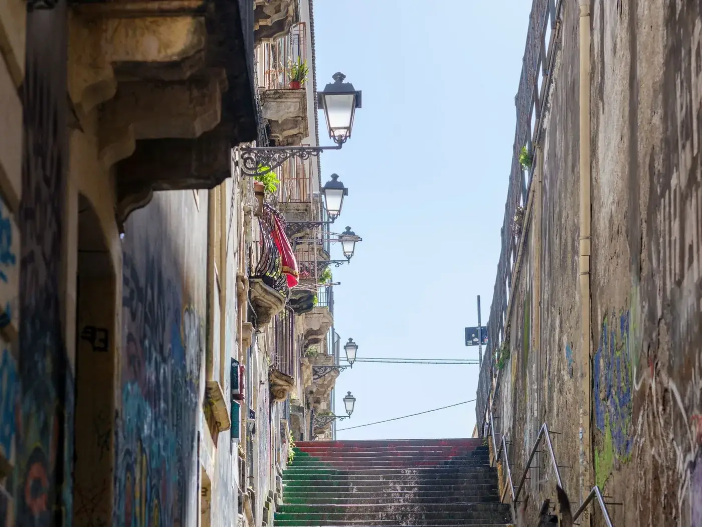 Charming view of historic stairway with balconies and street lamps leading to Catania's city center.