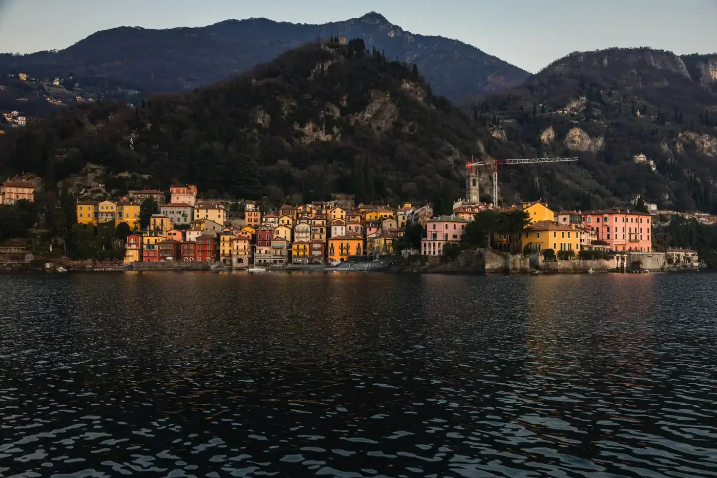 Charming Italian town on Lake Como with colorful houses at dusk, surrounded by mountains.