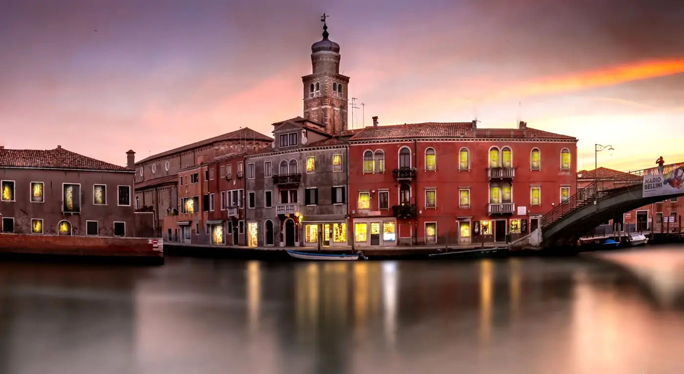 Beautiful sunset over a canal with historic buildings in Venice, Italy.