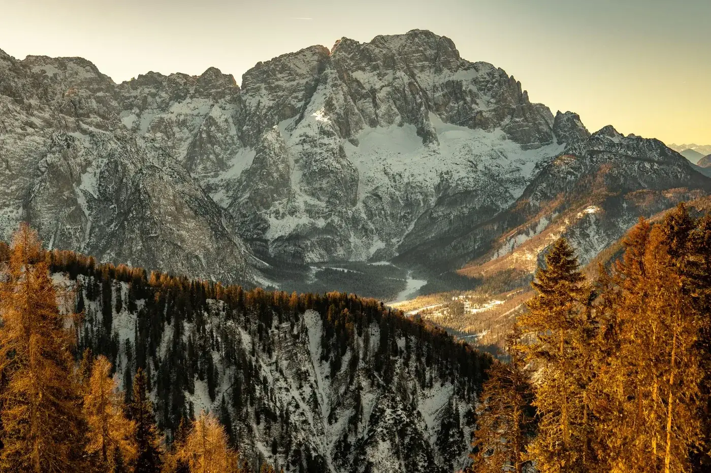 Breathtaking view of the Julian Alps during a winter sunrise with snow-capped peaks and golden light.