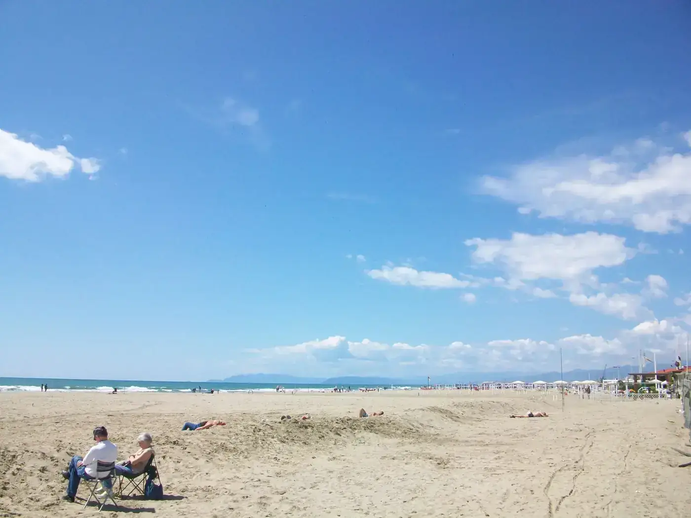 A relaxing beach scene with people lounging under a clear blue sky. Perfect for vacation imagery.