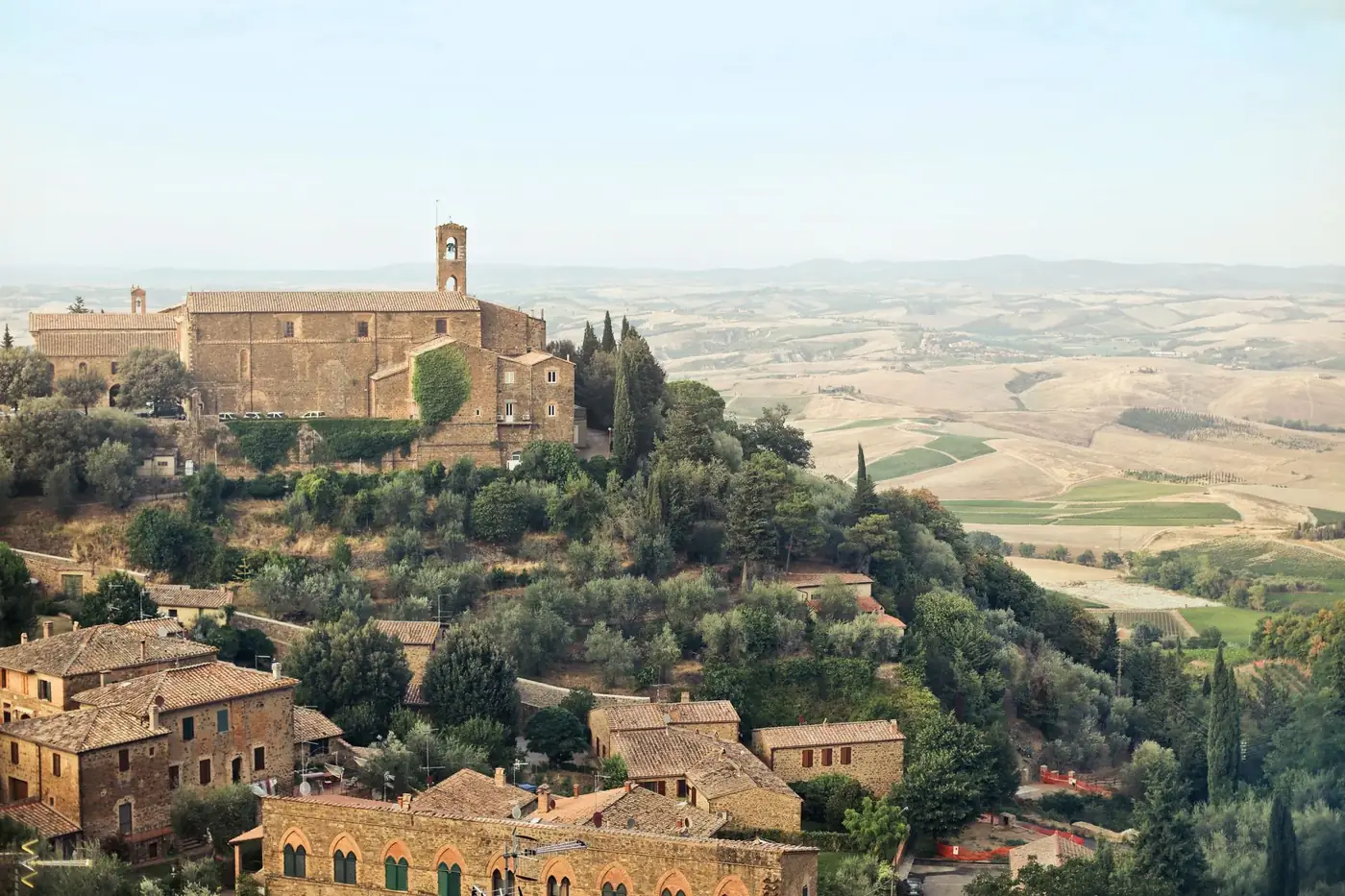 From above picturesque view of ancient town with brick buildings and green trees located on hill in sunny day in country